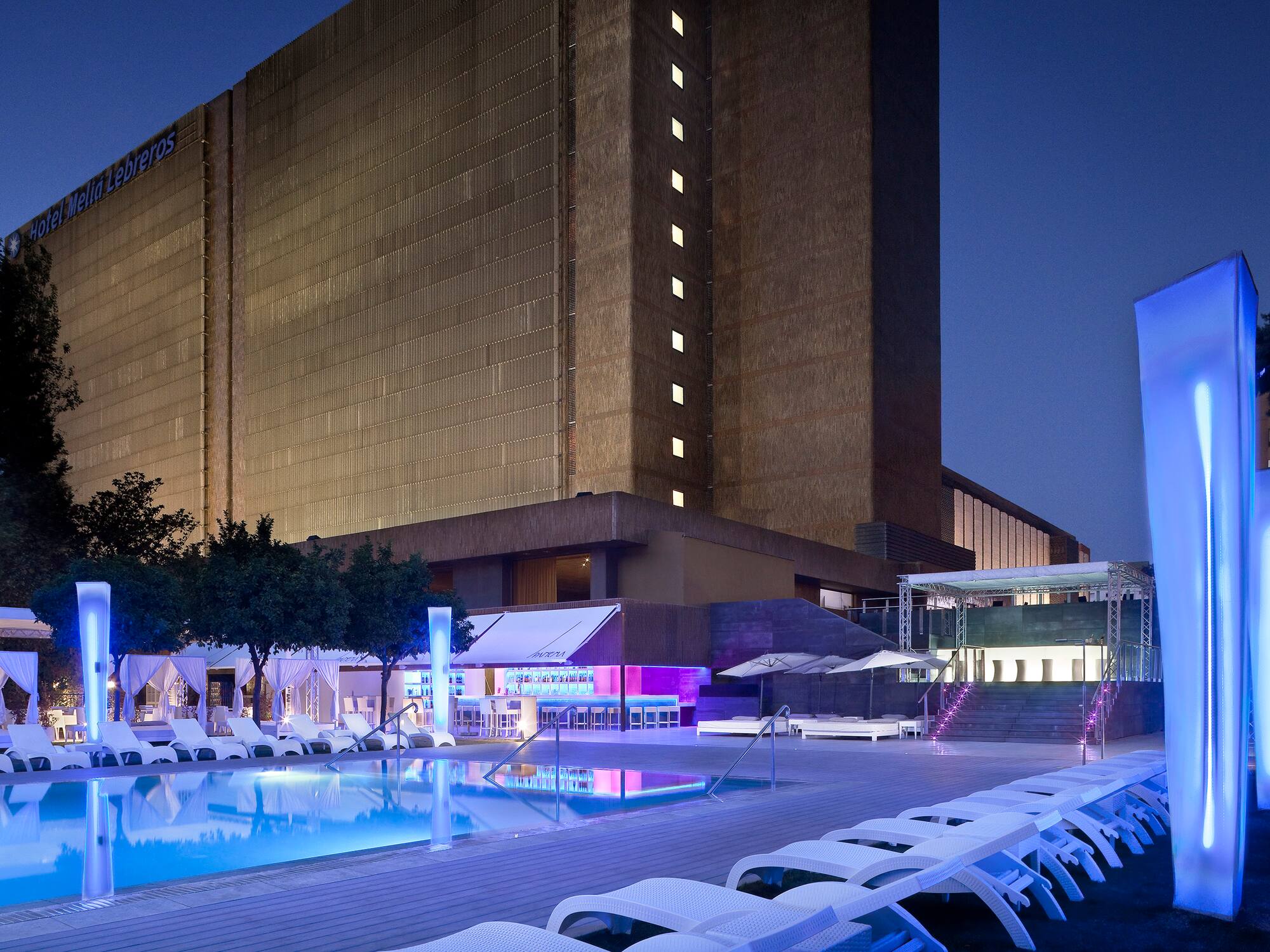 a pool and lounge chairs in front of a building