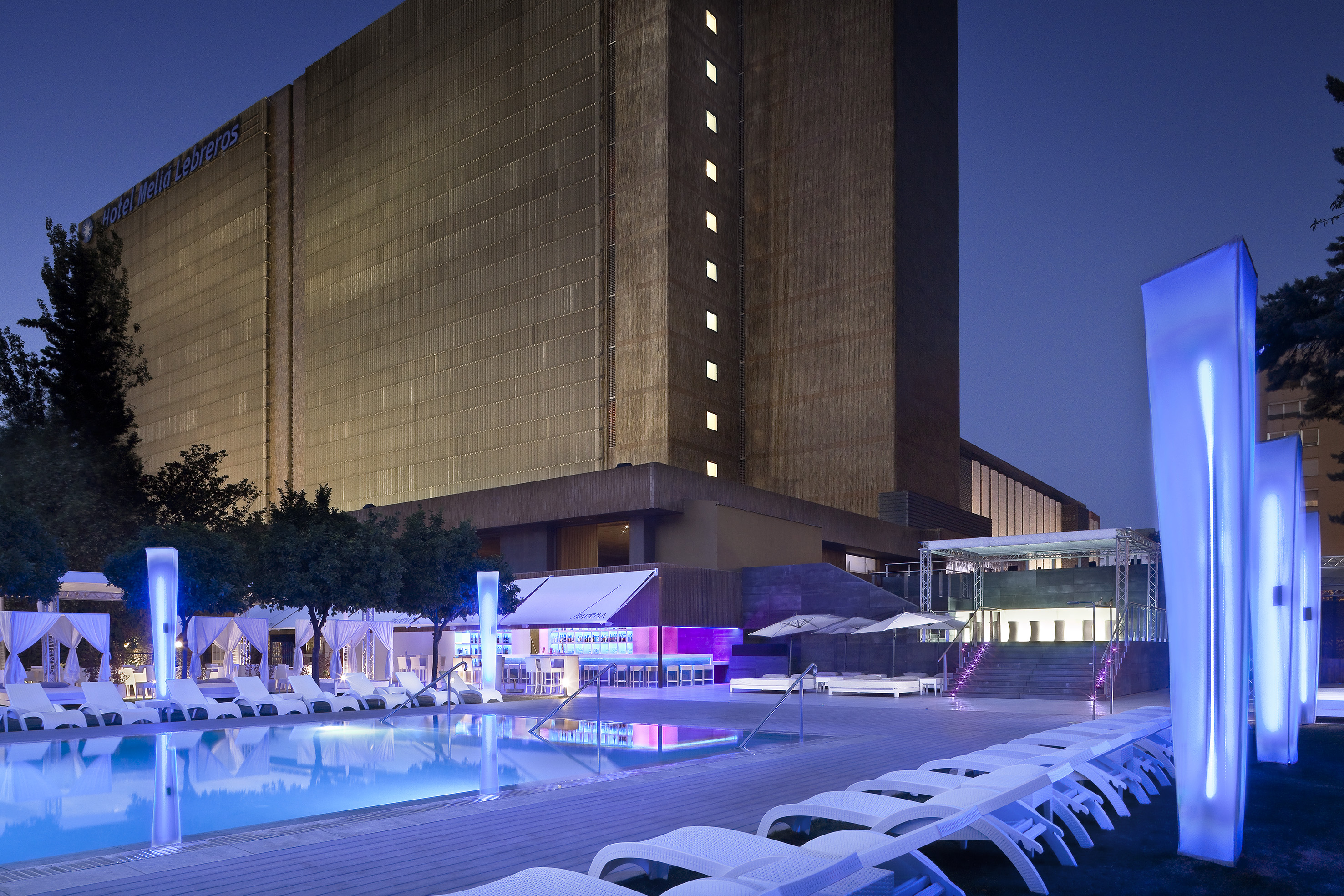 a pool and lounge chairs in front of a building