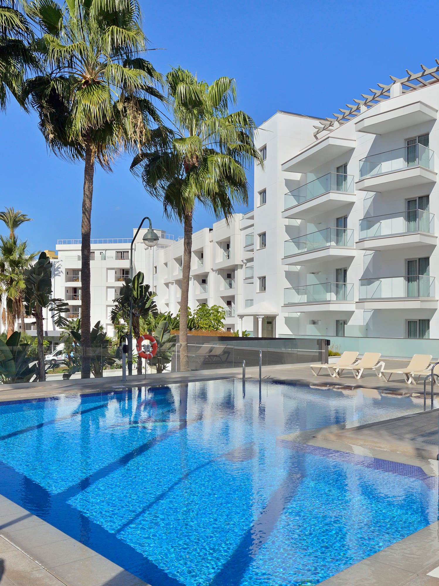 a pool with palm trees and a building in the background
