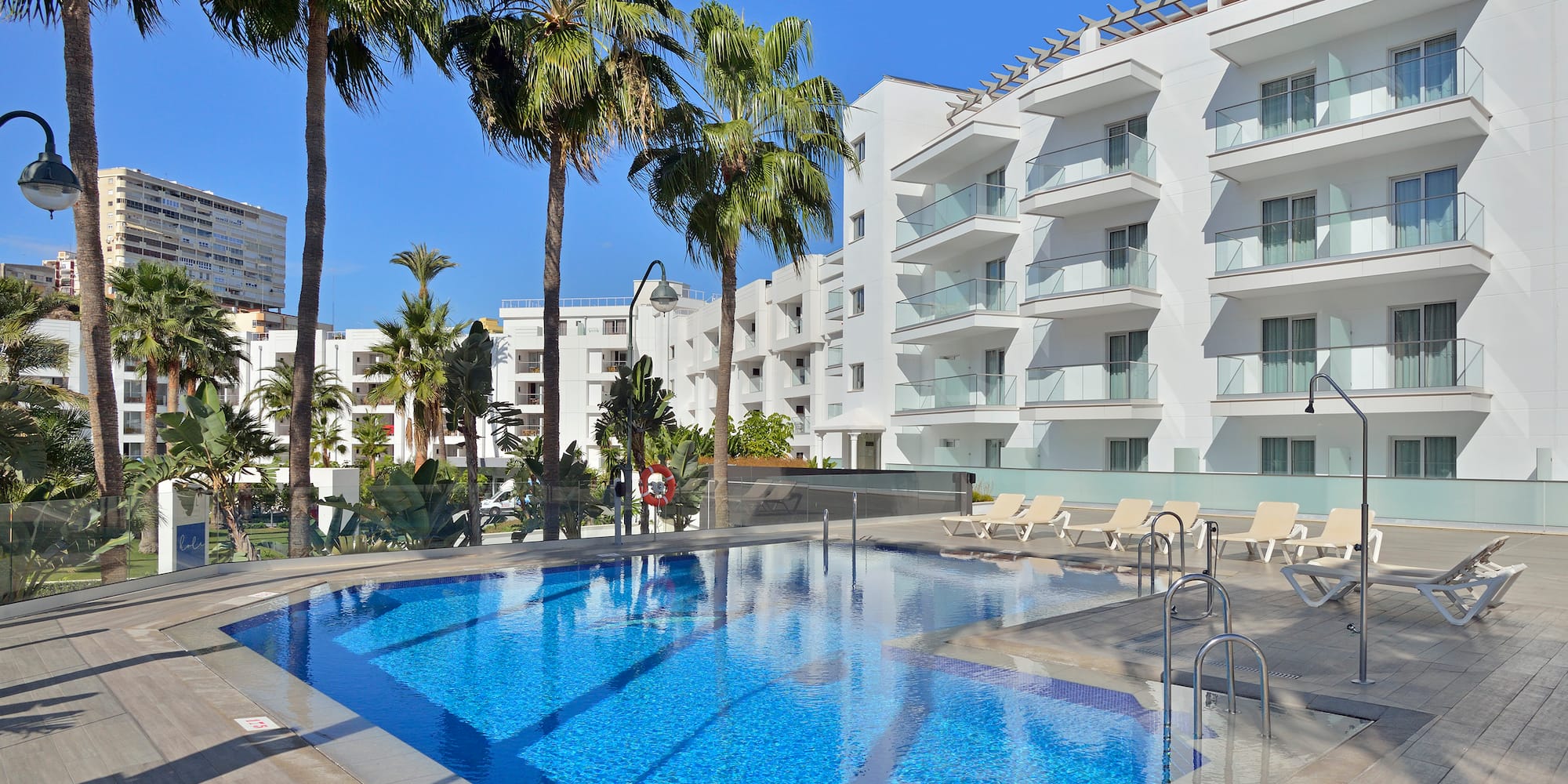 a pool with palm trees and a building in the background