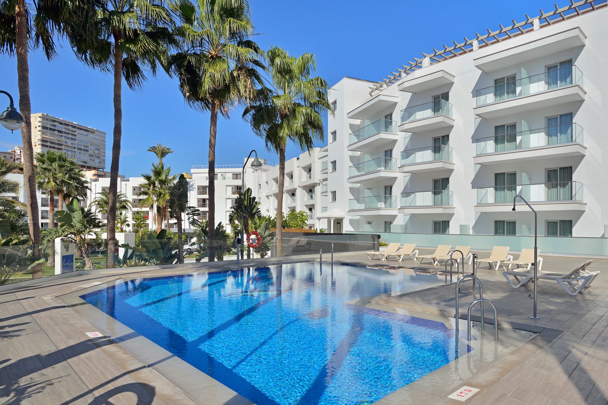 a pool with palm trees and a building in the background