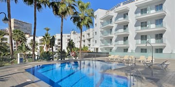 a pool with palm trees and a building in the background