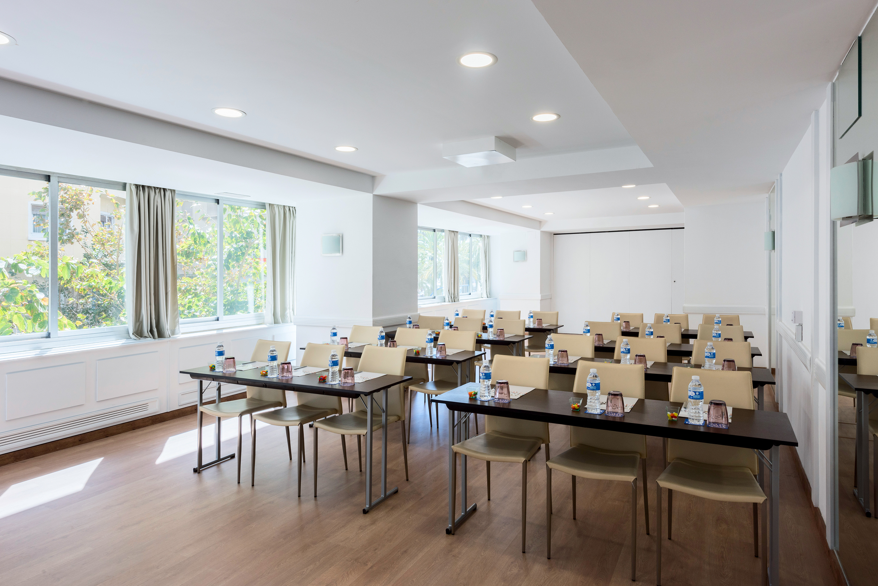 Modern meeting room with natural light, tables, chairs, and bottled water. - Postiguet - Hotel Alicante Gran Sol Affiliated by Meliá, 阿利坎特