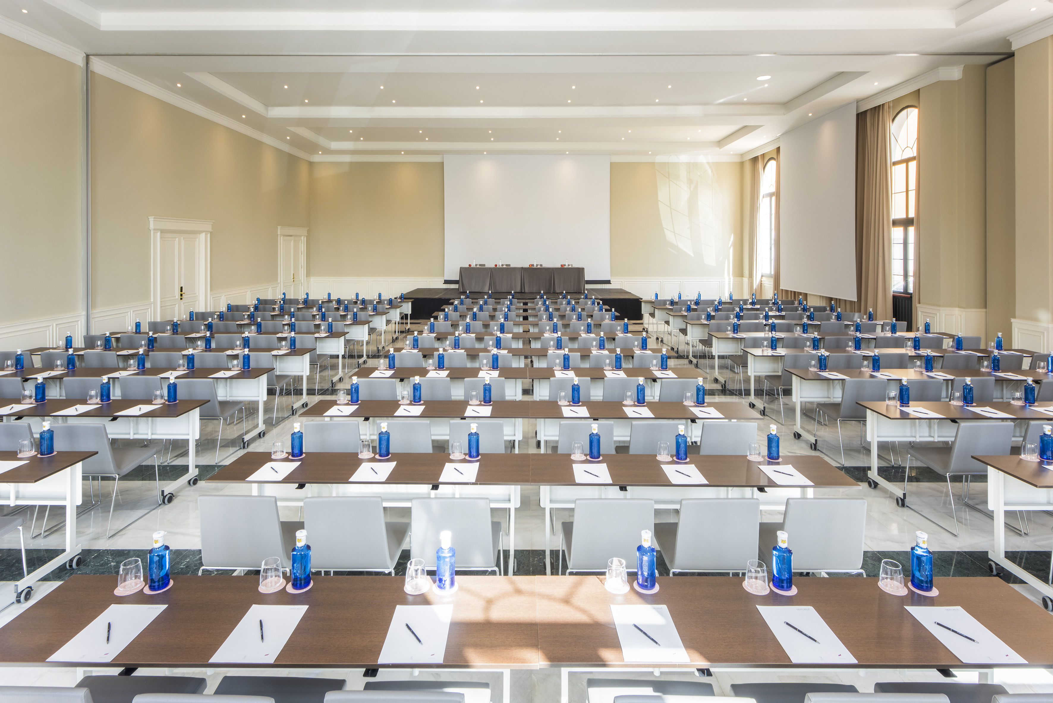 Conference room with classroom setup, water bottles, and presentation screen.