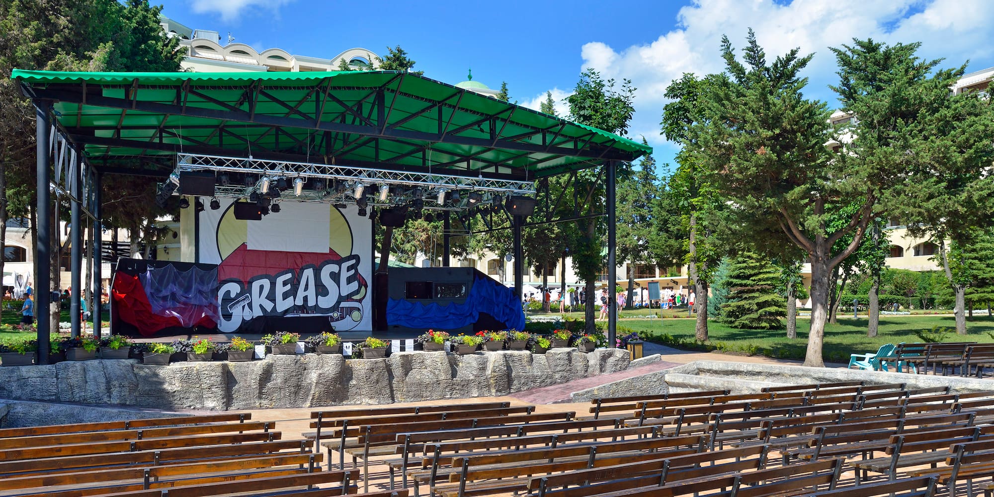 a stage with a green roof and benches in front of it