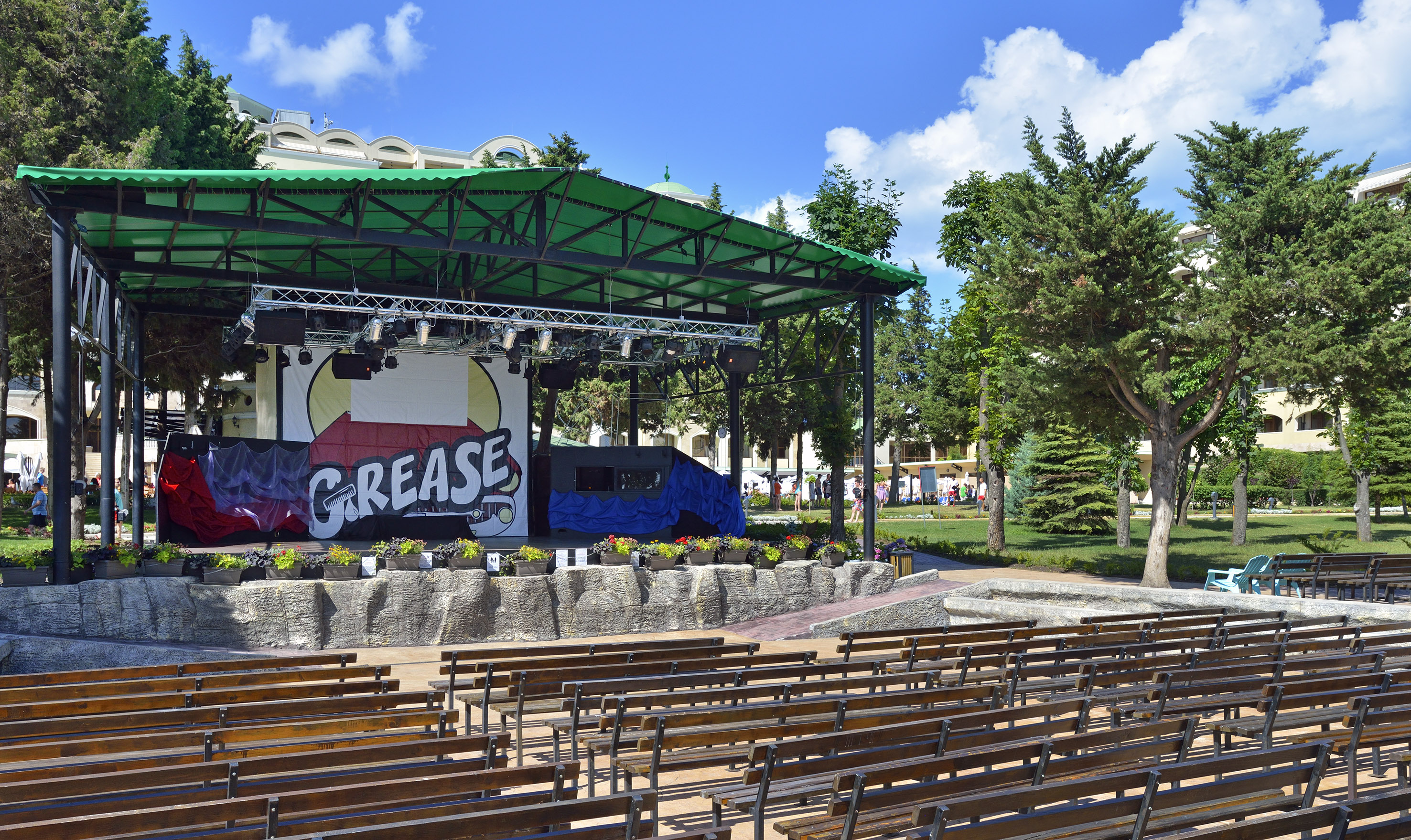 a stage with a green roof and benches in front of it