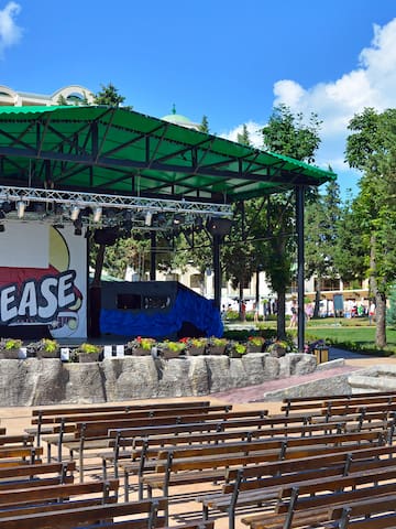 a stage with a green roof and benches in front of it
