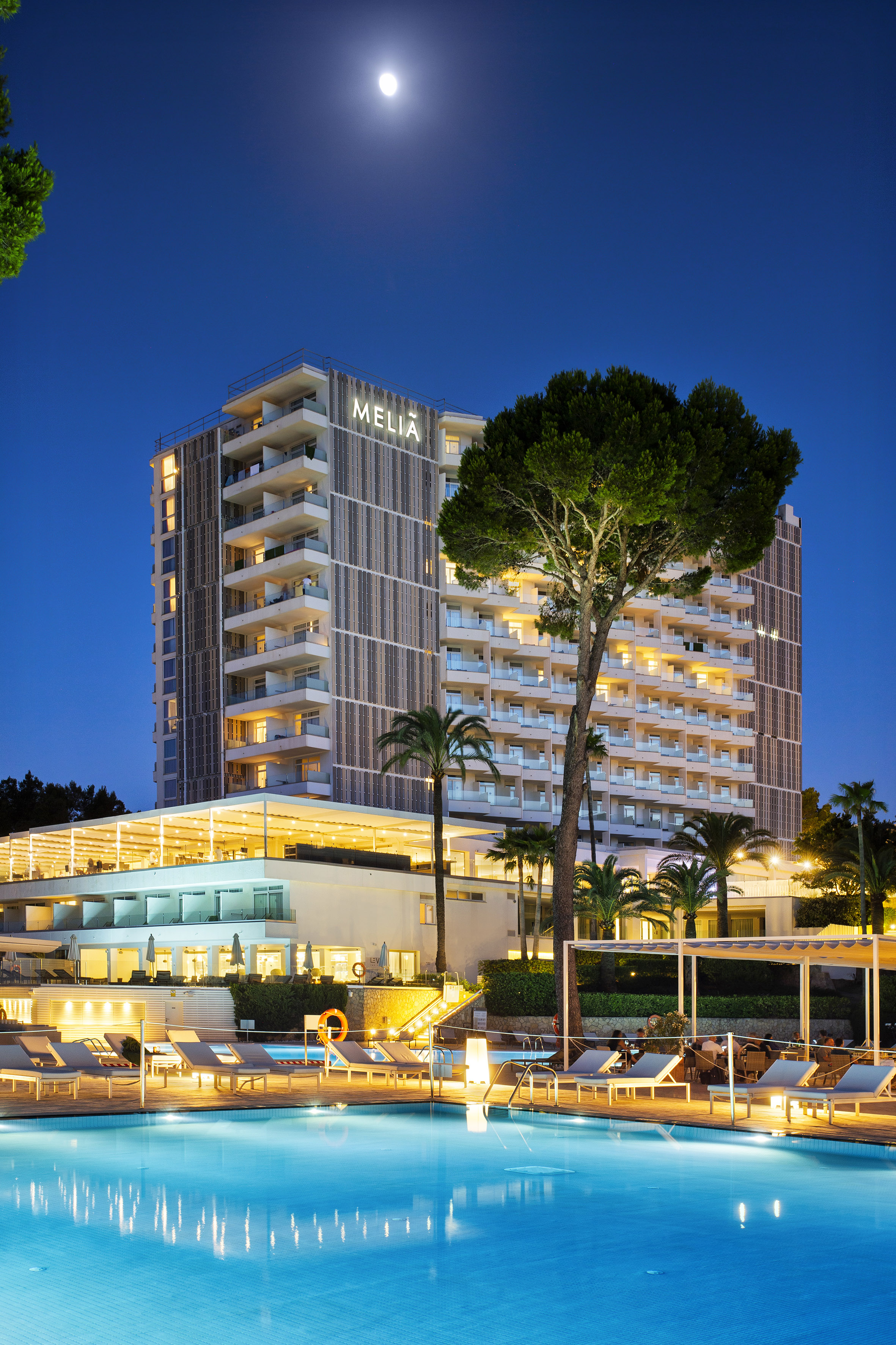 Meliá hotel and pool illuminated at night under the moon.