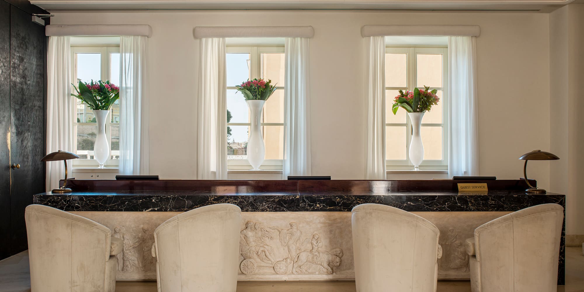 a row of white chairs in a room with windows