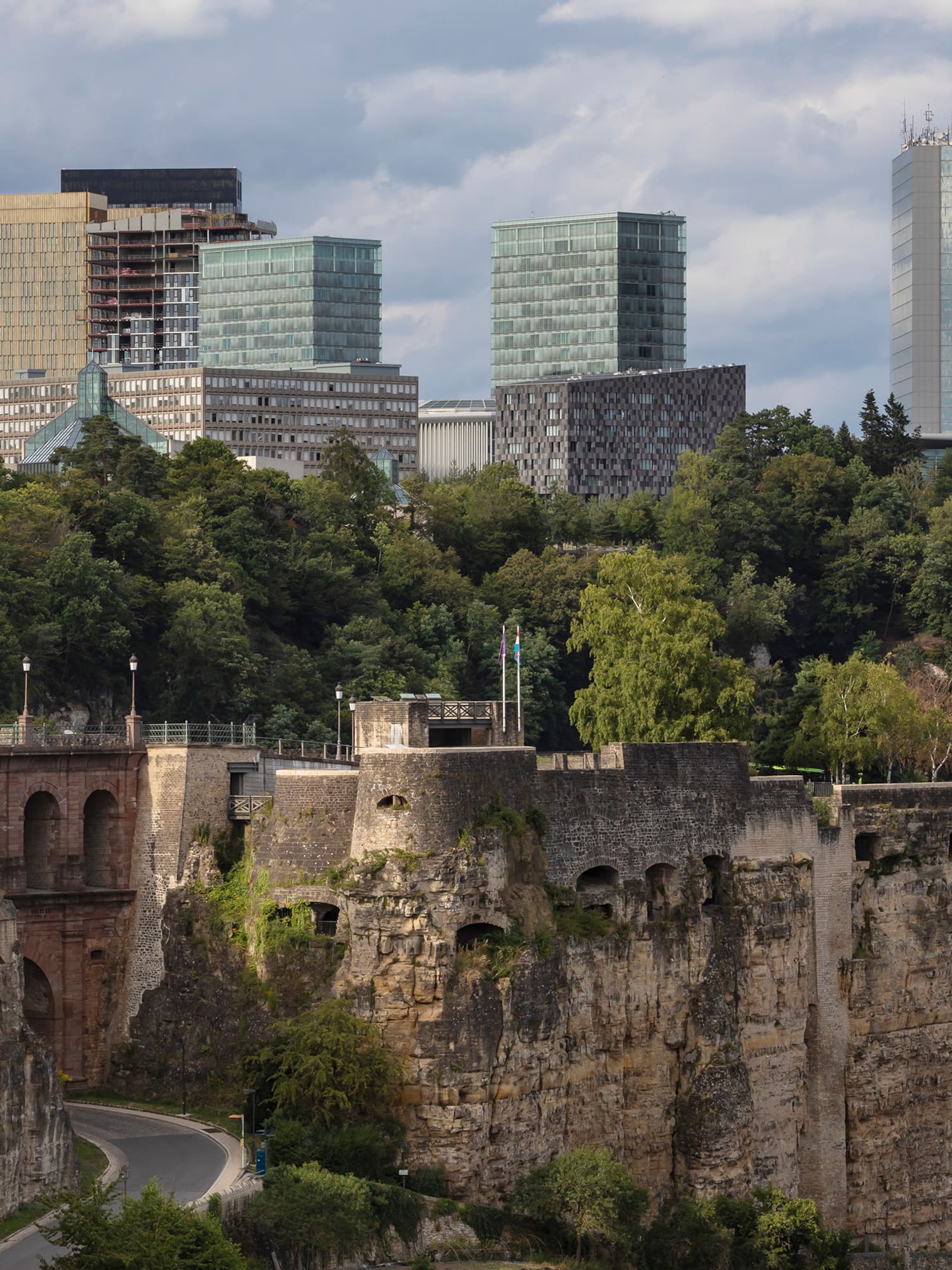a stone wall with trees and buildings in the background