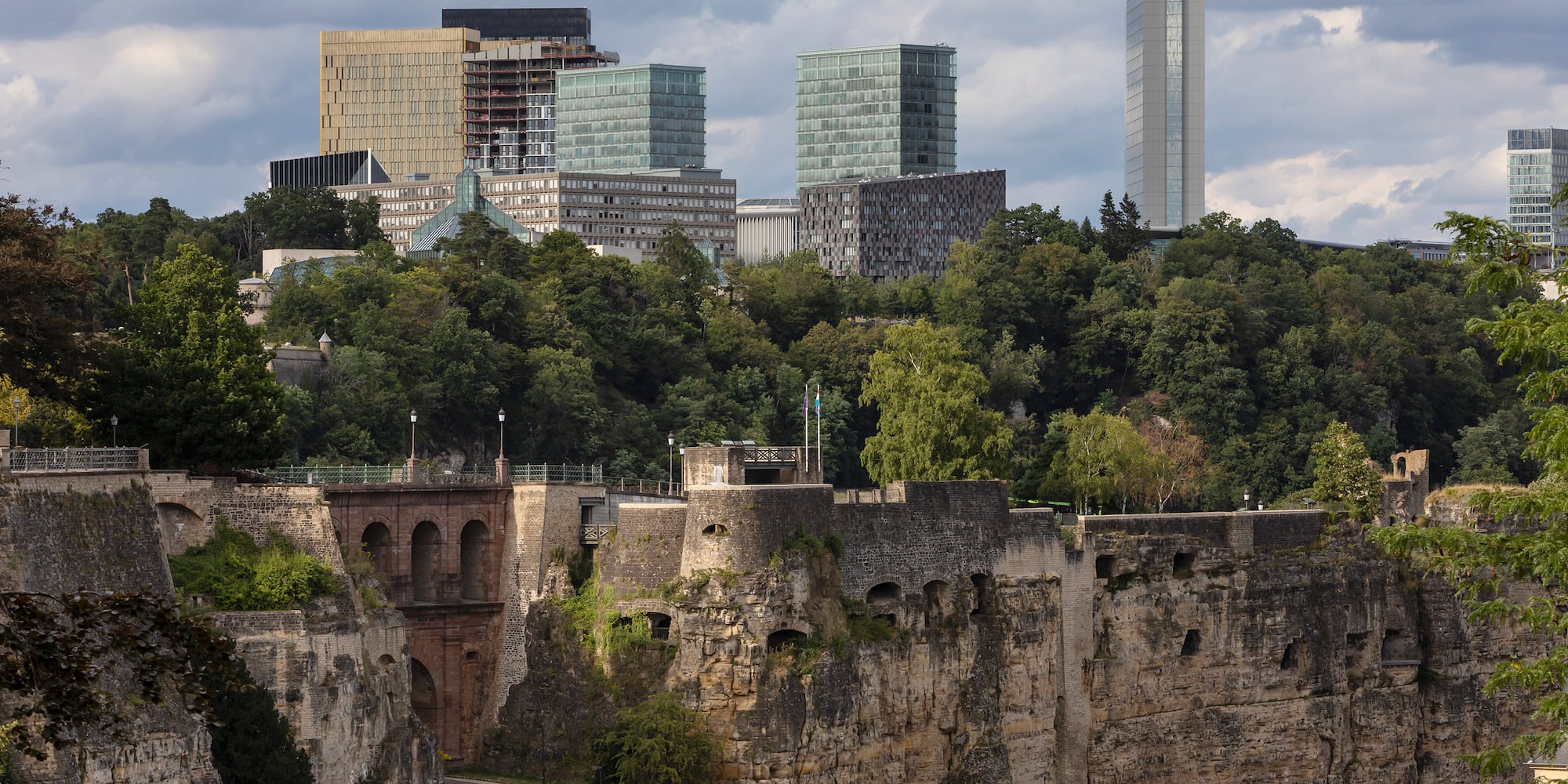 a stone wall with trees and buildings in the background