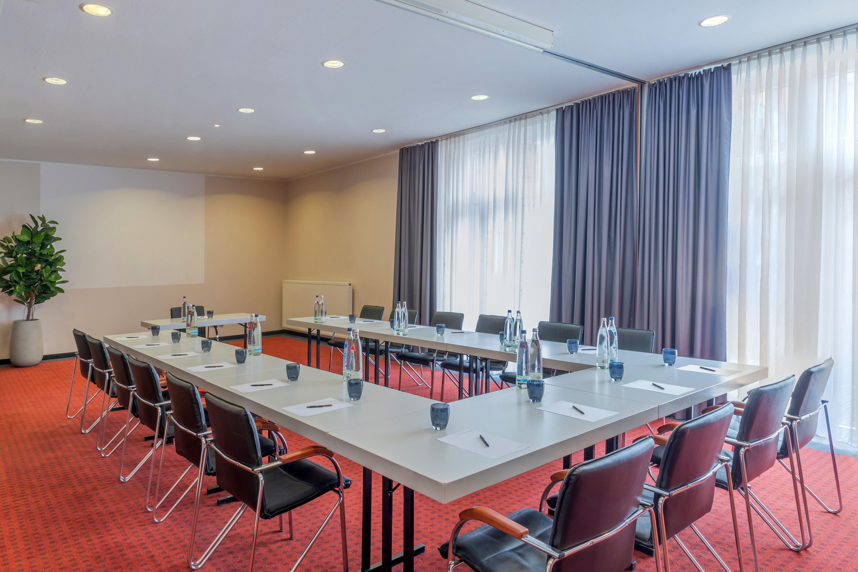 U-shape conference room with black chairs, red carpet, and projector wall.