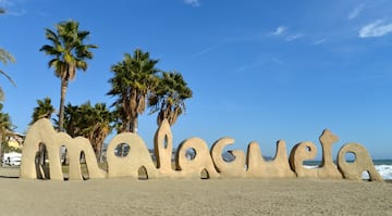 a large sand sculpture of a beach with palm trees and blue sky