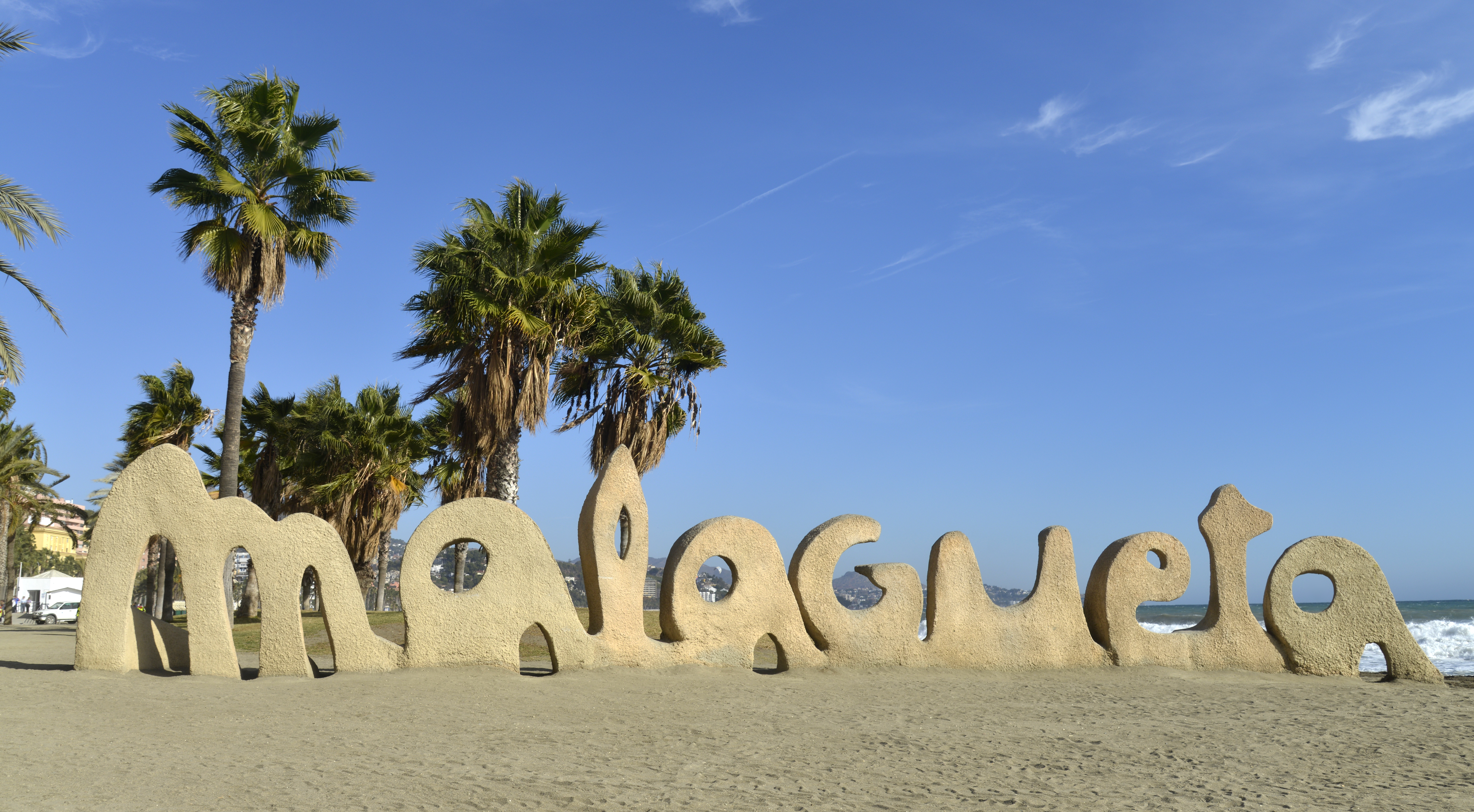 a large sand sculpture of a beach with palm trees and blue sky