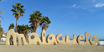a large sand sculpture of a beach with palm trees and blue sky