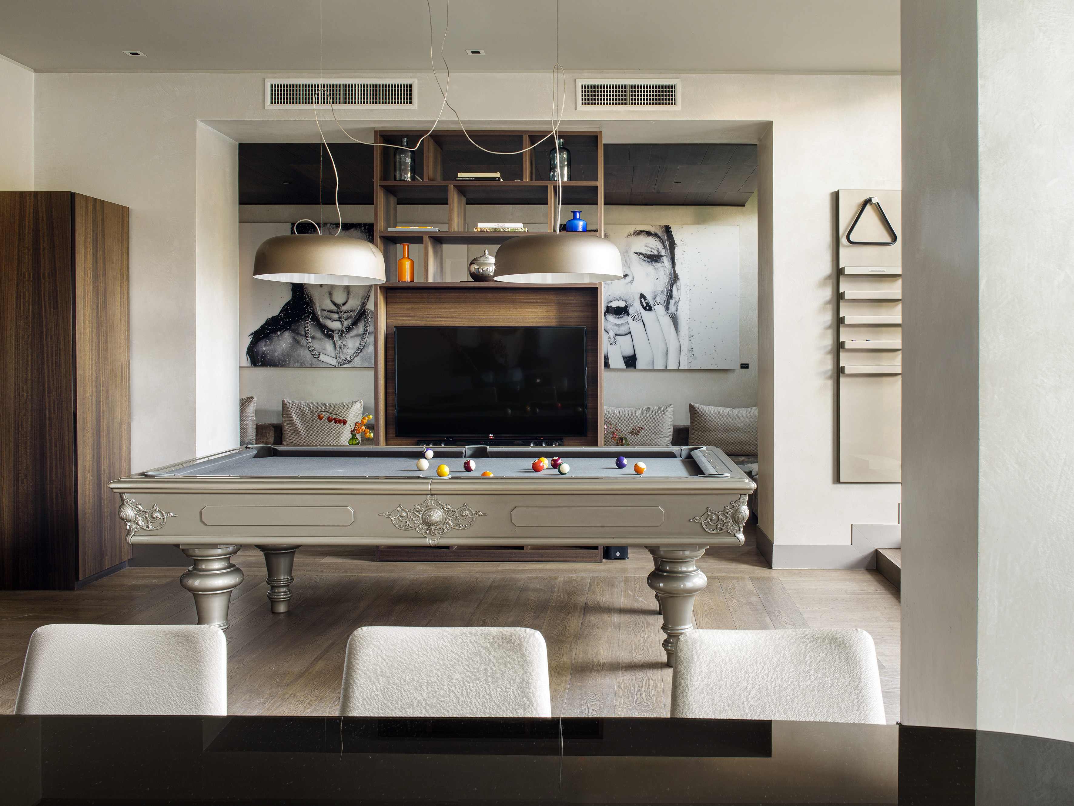 Ornate billiard table in a modern game room with TV and large artworks.
