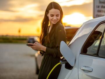 a woman holding a phone next to a car