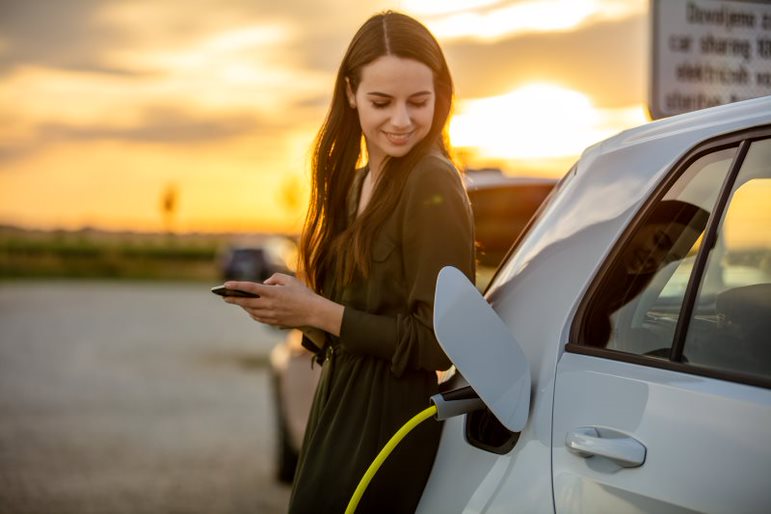 a woman holding a phone next to a car