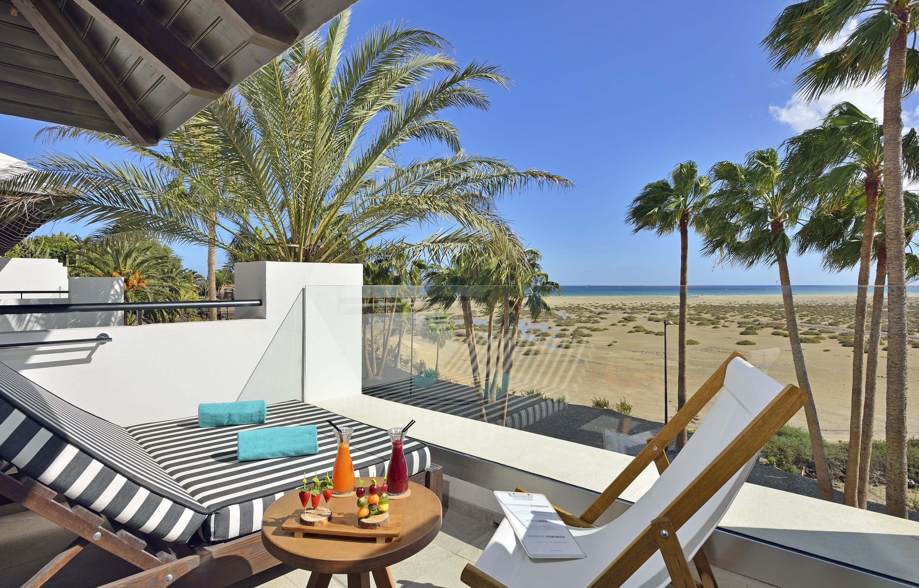 a deck with a table and chairs and a beach view