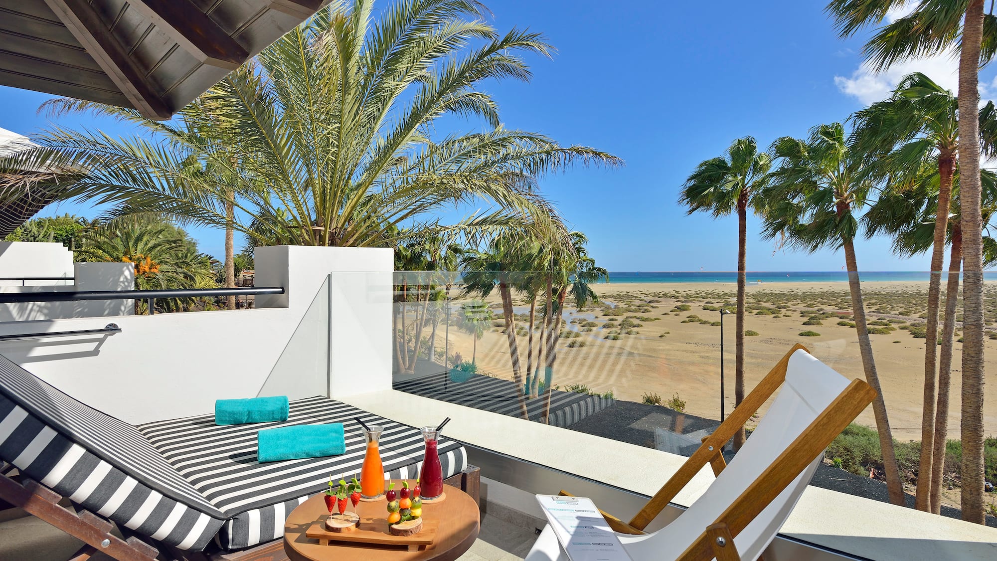 a deck with a table and chairs and a beach view
