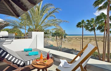 a deck with a table and chairs and a beach view