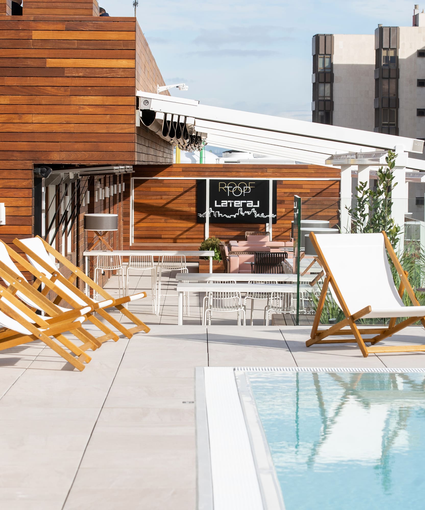 a pool with chairs and tables on a rooftop