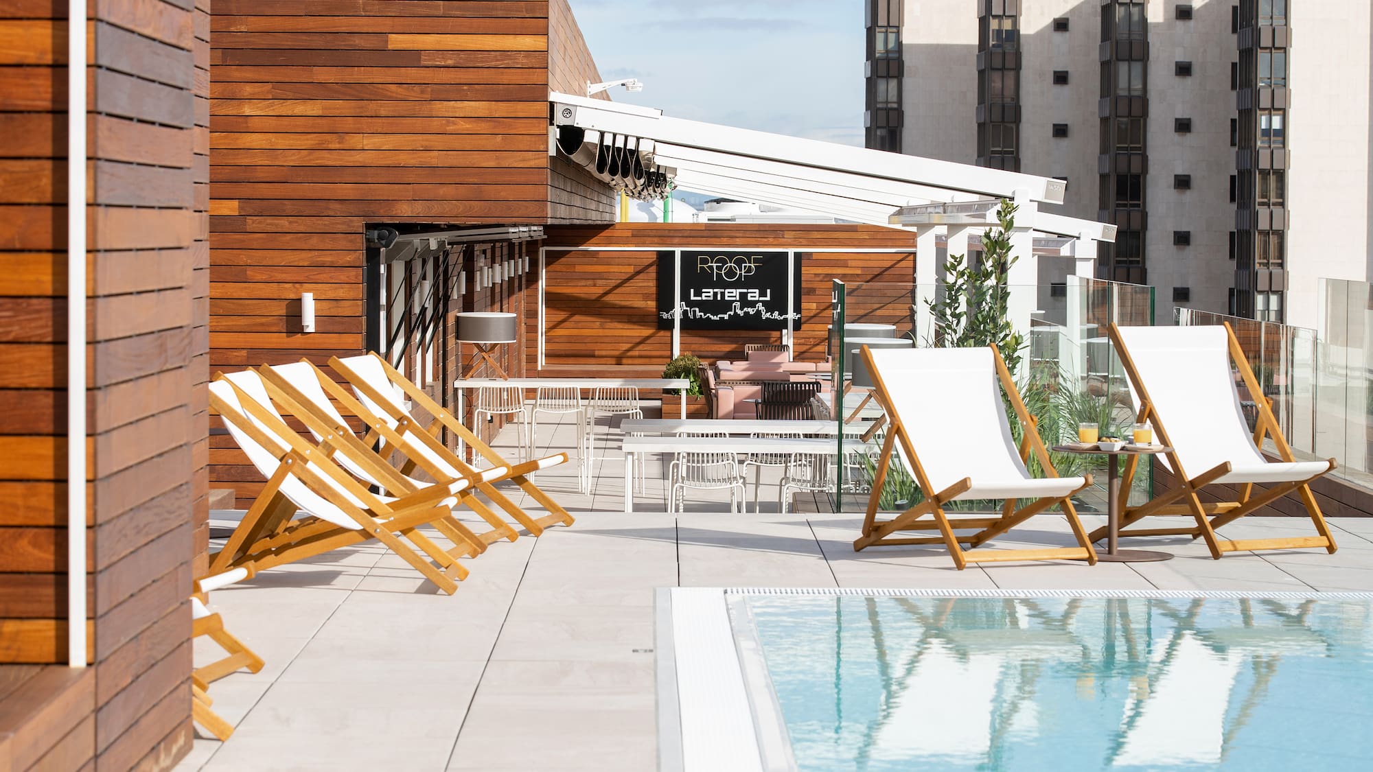 a pool with chairs and tables on a rooftop