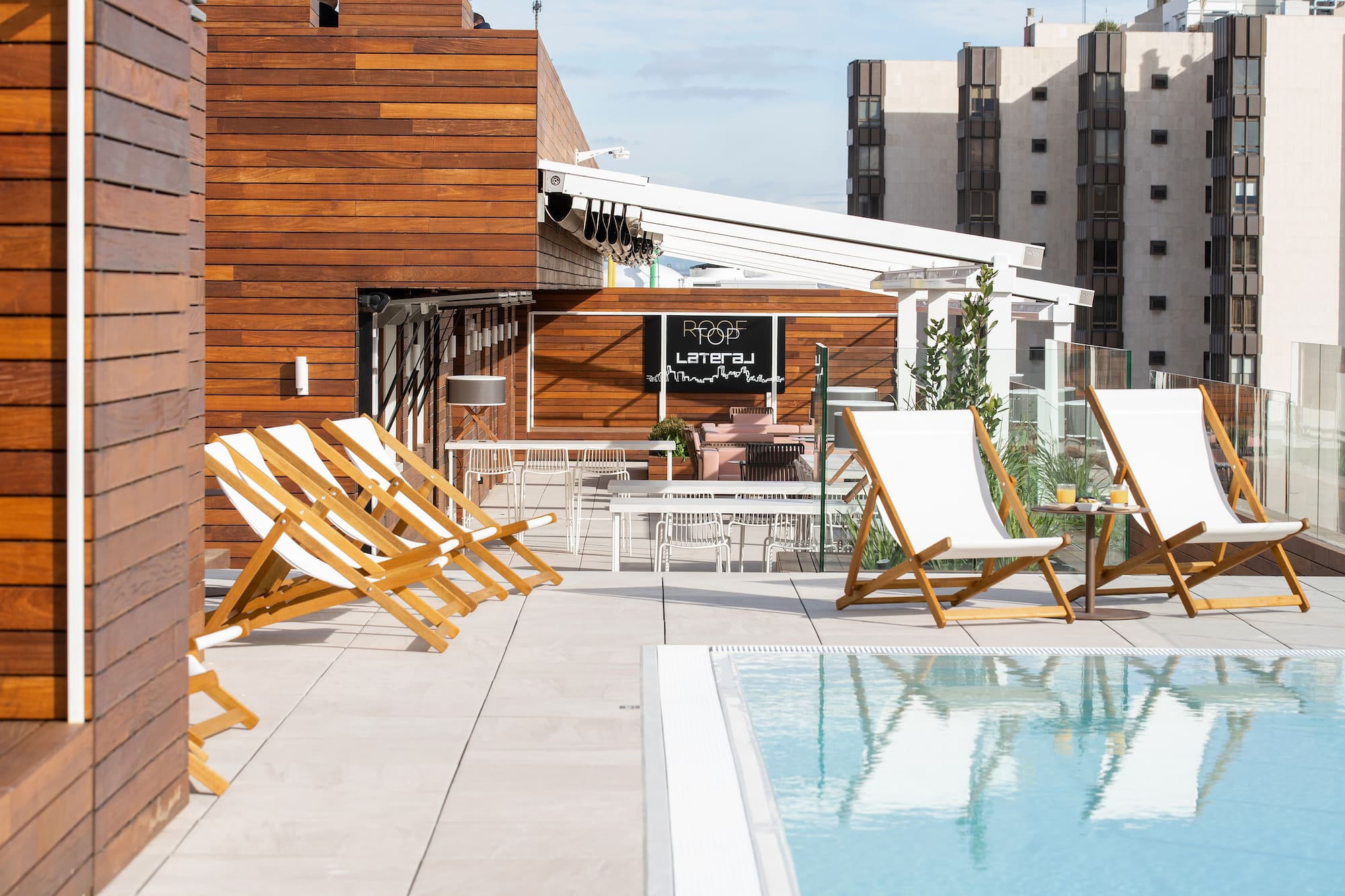 a pool with chairs and tables on a rooftop