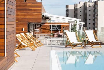 a pool with chairs and tables on a rooftop