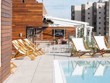 a pool with chairs and tables on a rooftop