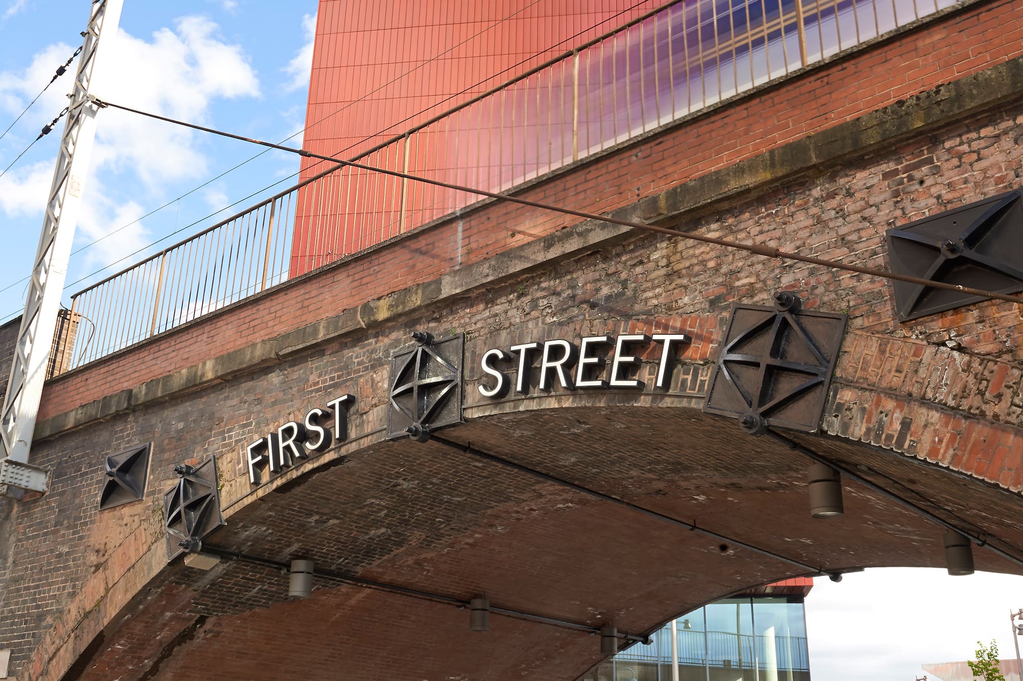 Red Innside hotel building above First Street brick archway, Manchester.