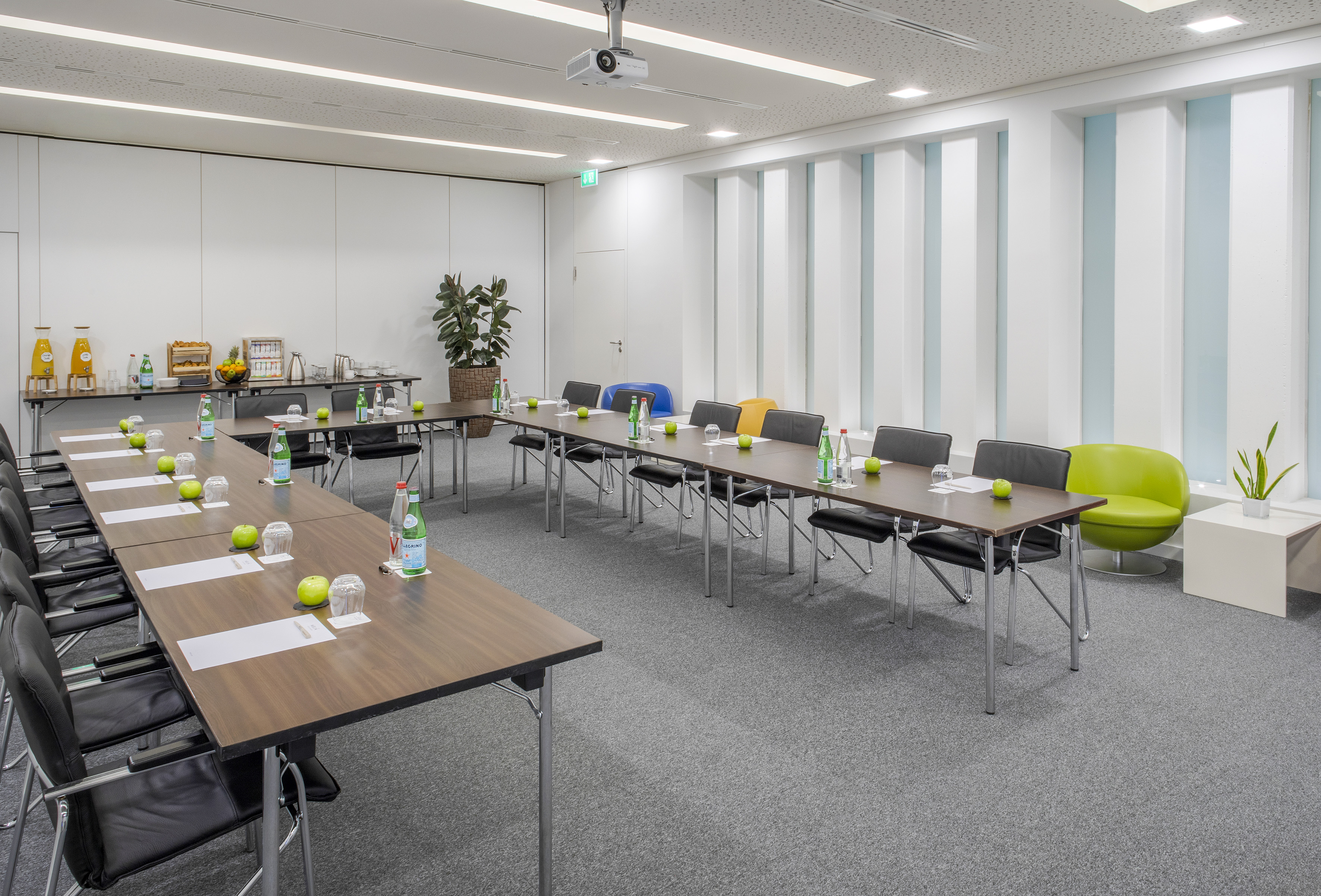 U-shaped conference room with projector, refreshments, and modern design.