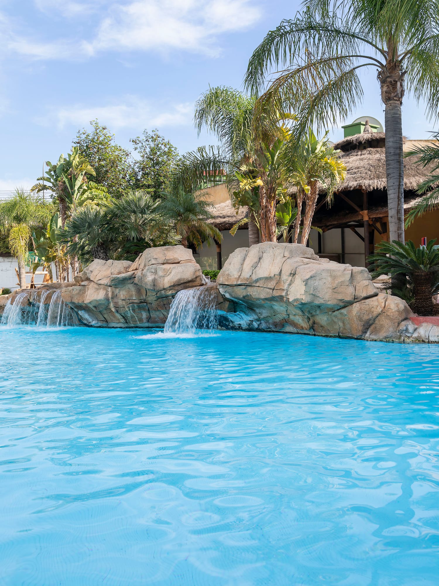 a pool with a waterfall and palm trees