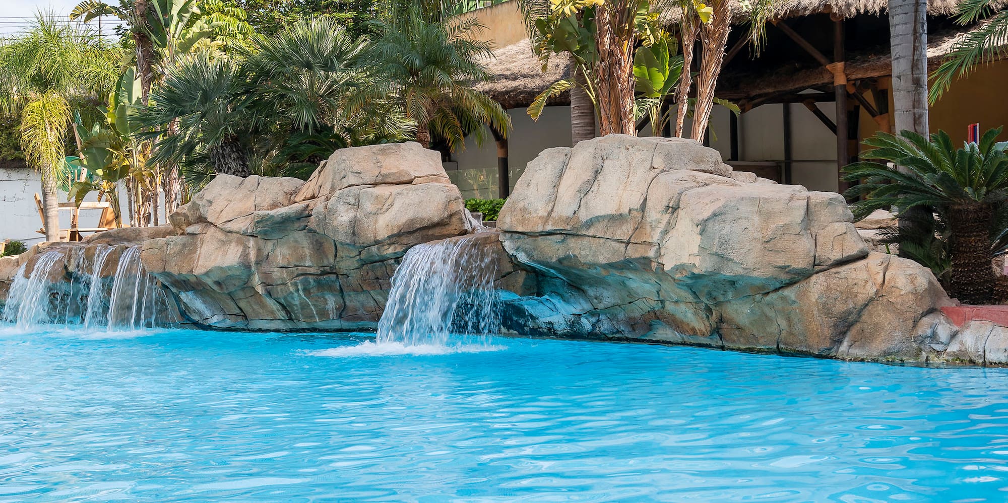 a pool with a waterfall and palm trees