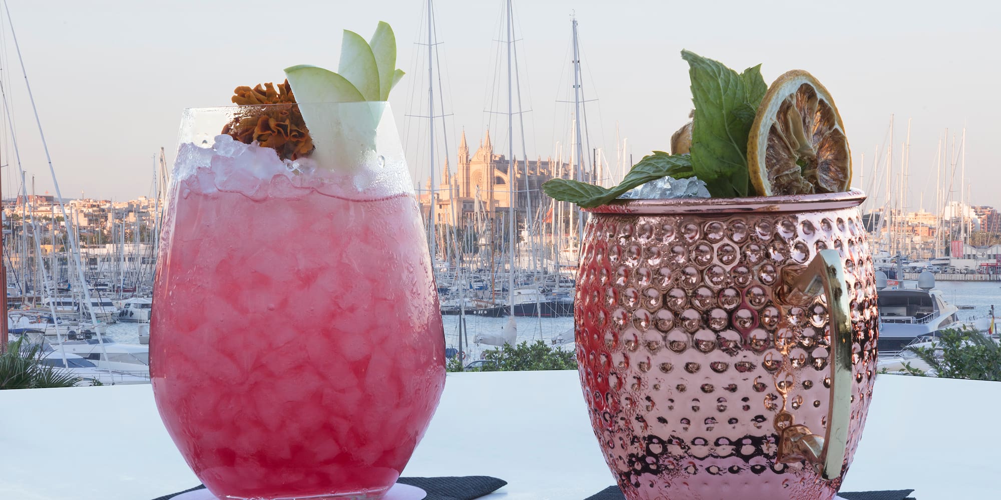 two glasses with ice and fruit on them