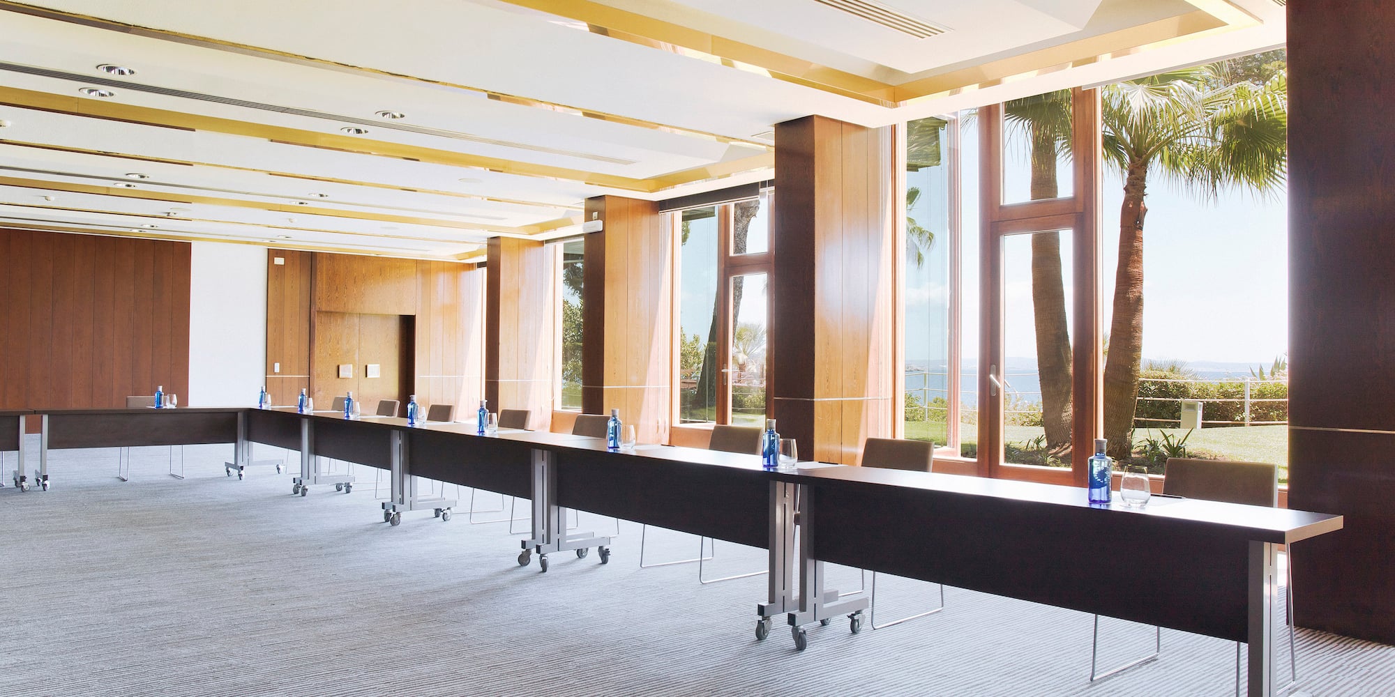 a long table with bottles in a room with windows