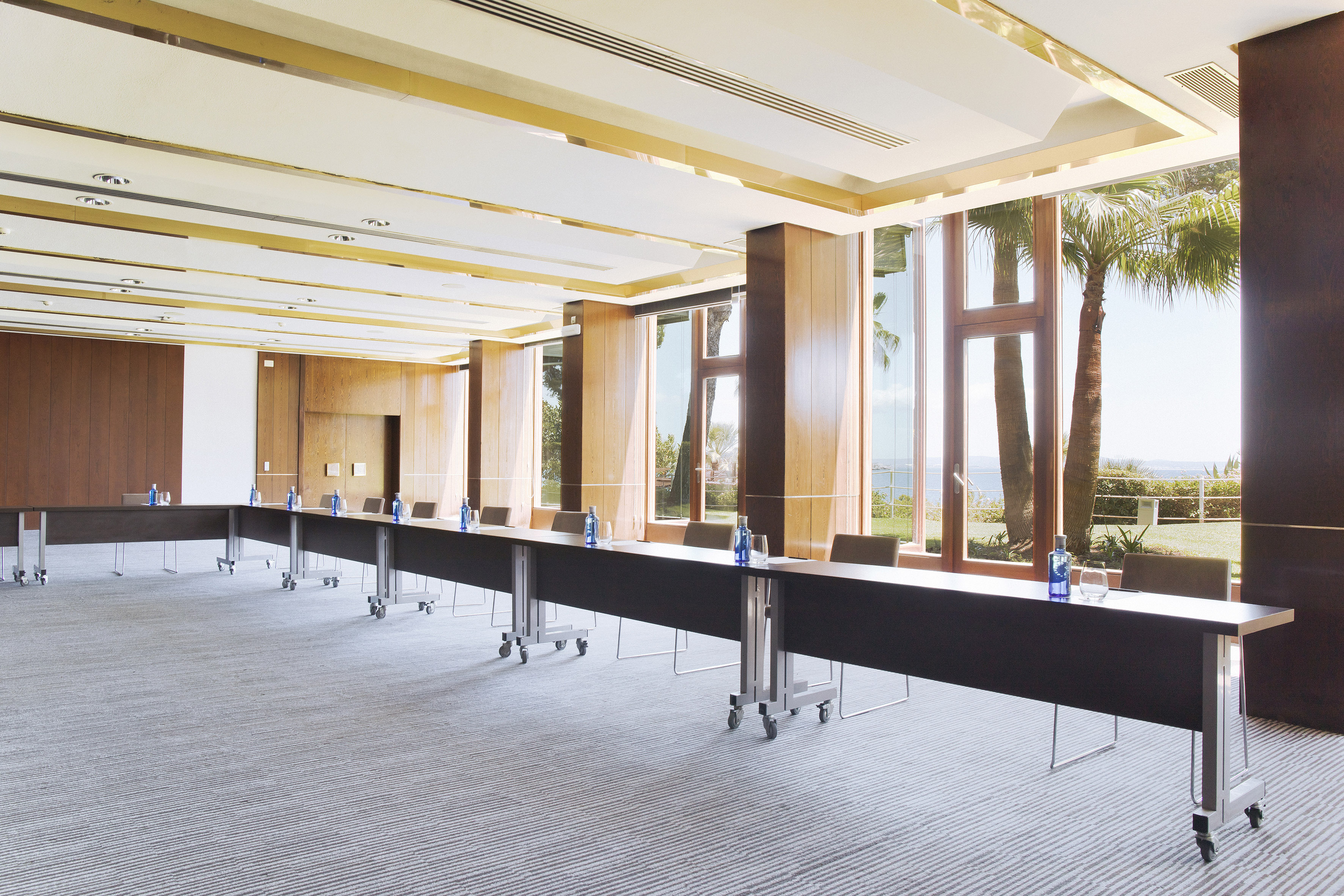 a long table with bottles in a room with windows