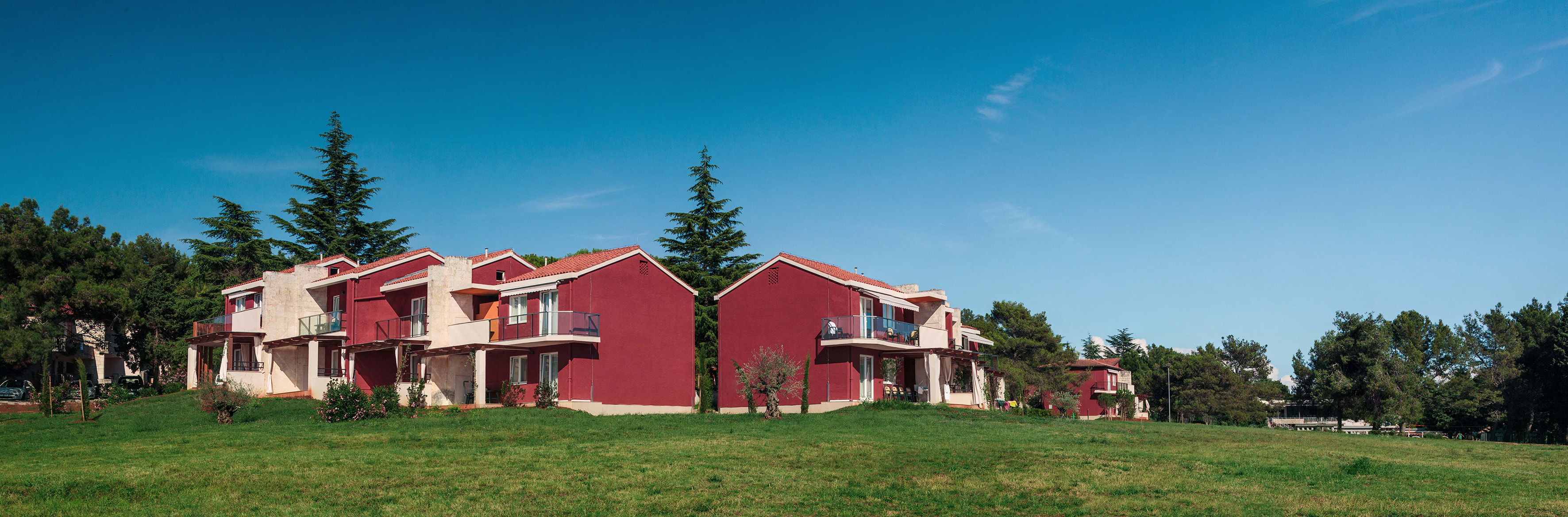 a group of red houses with trees in the background