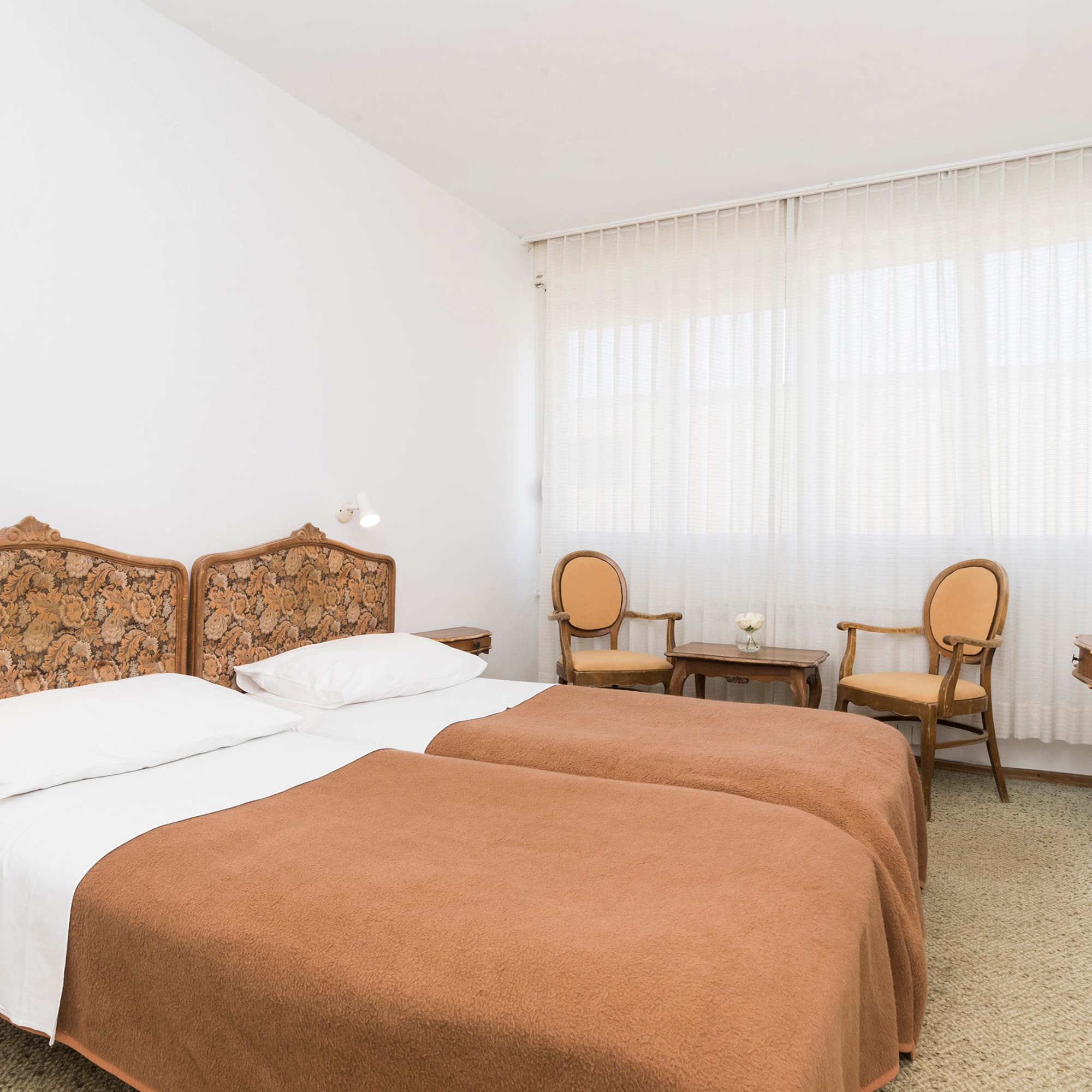 a room with two beds and chairs