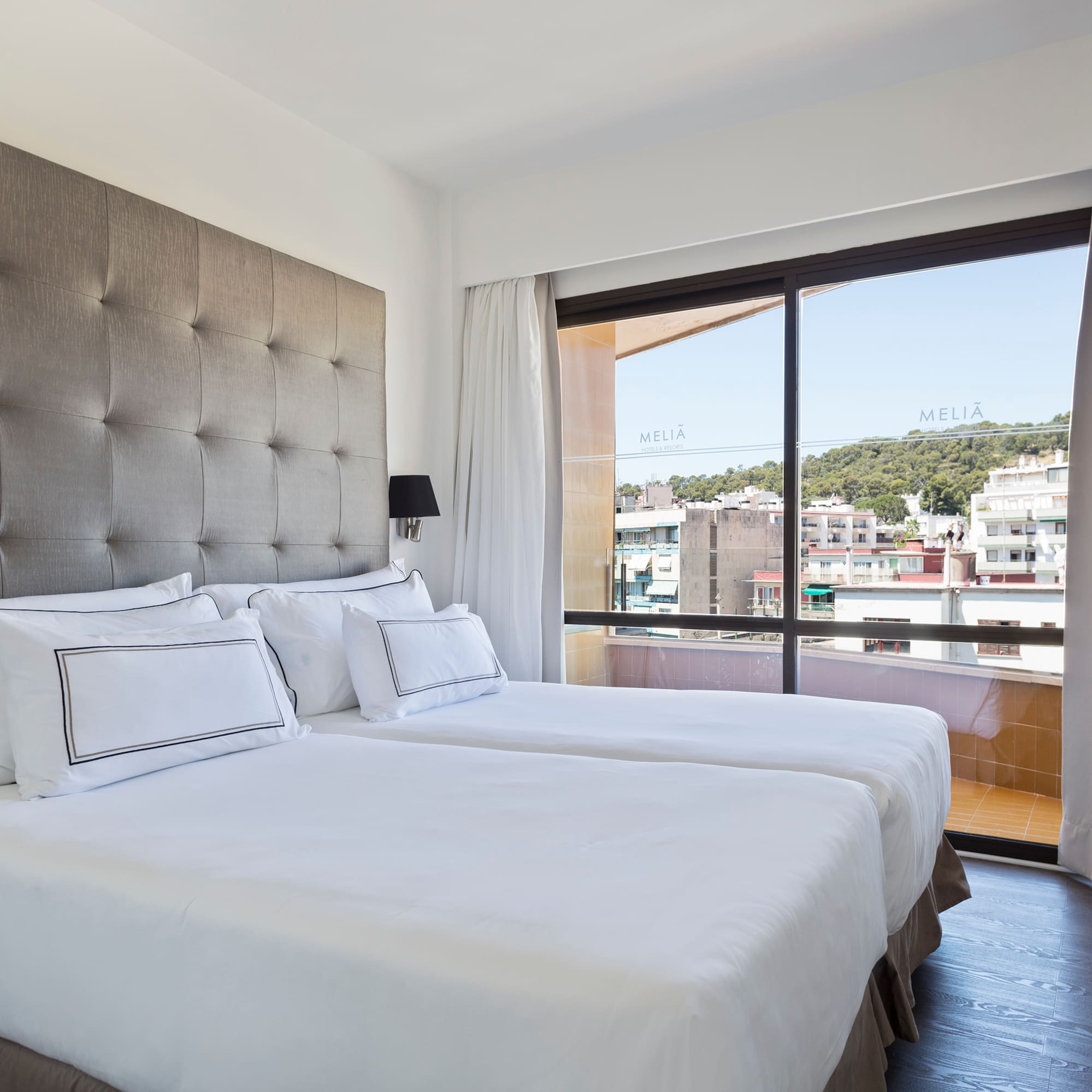 a bed with white sheets and a large window