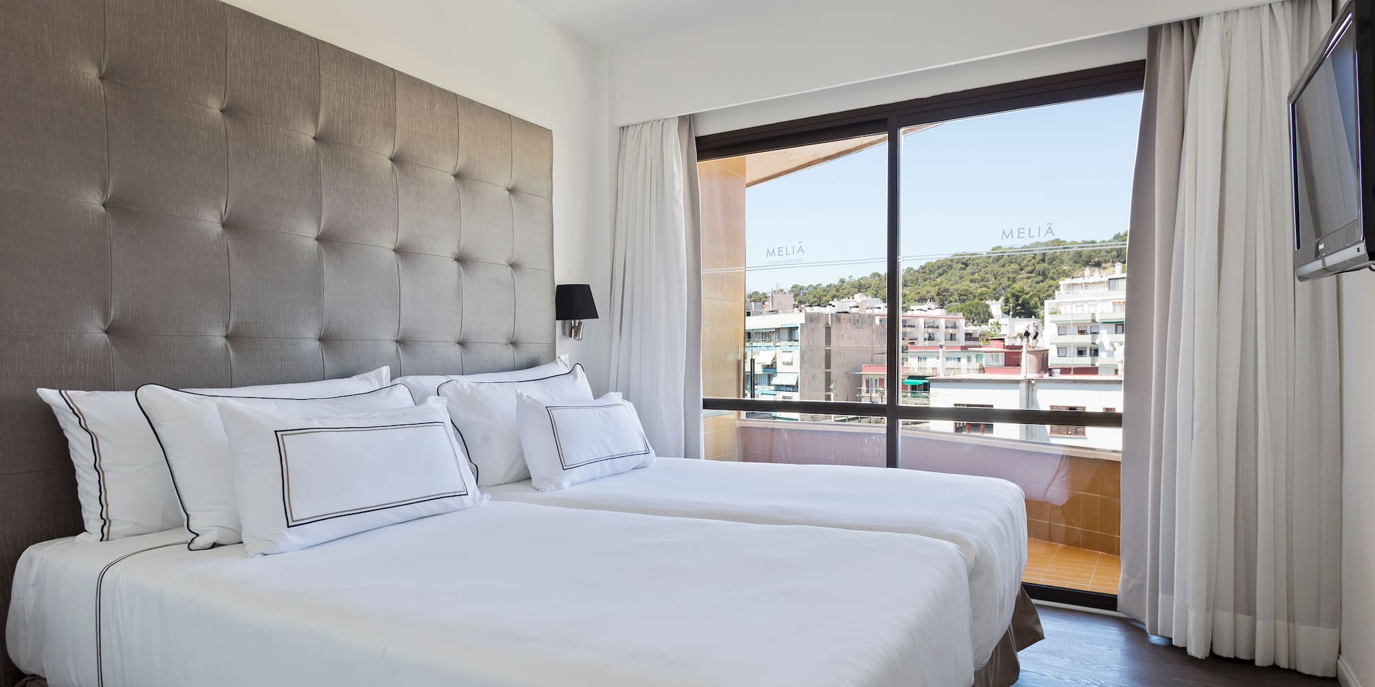 a bed with white sheets and a large window