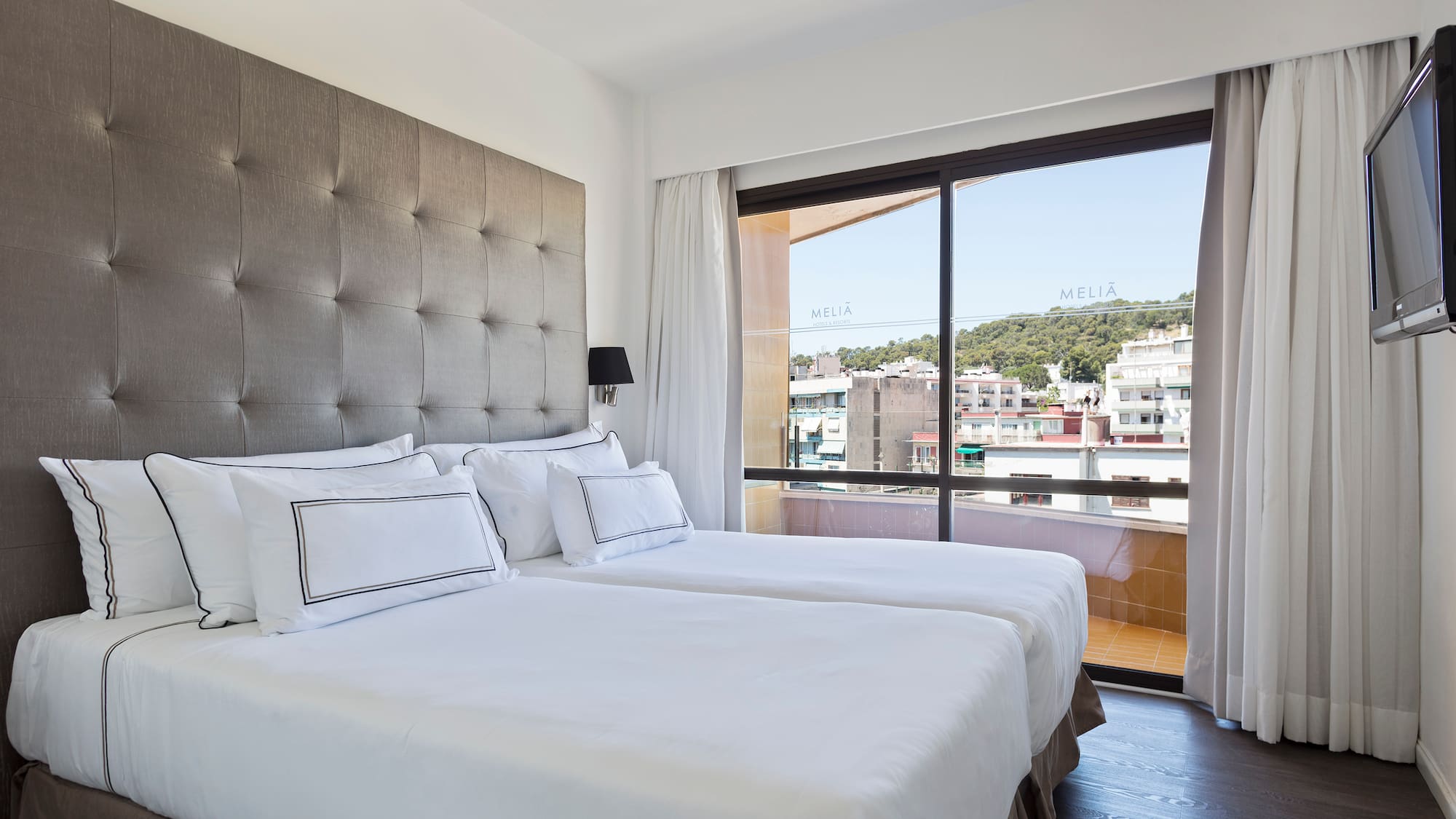 a bed with white sheets and a large window