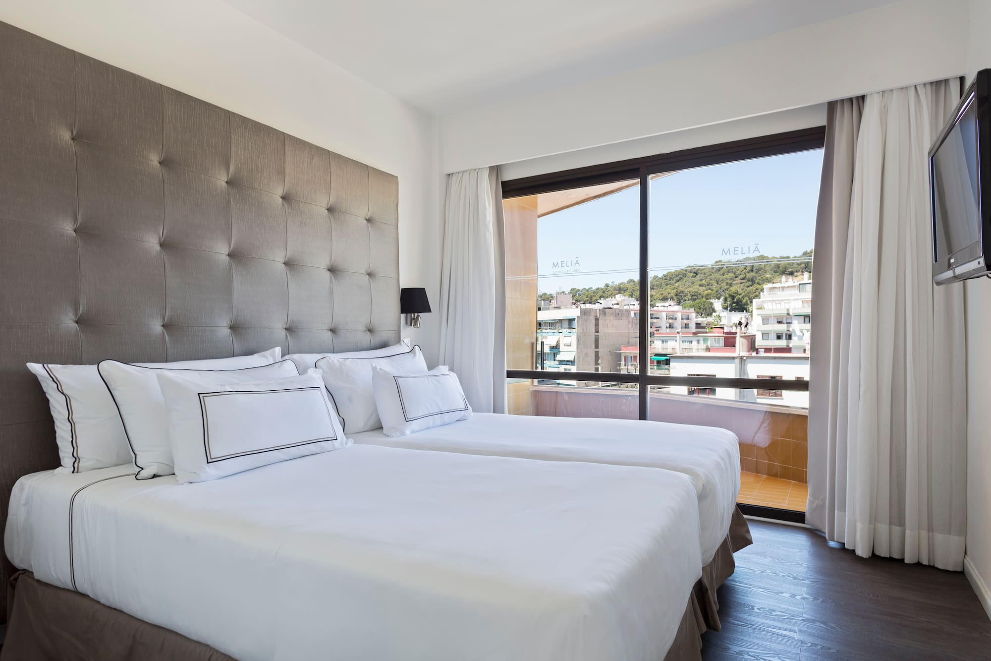 a bed with white sheets and a large window