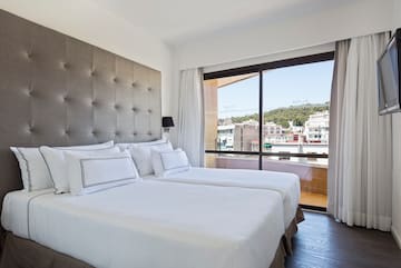 a bed with white sheets and a large window