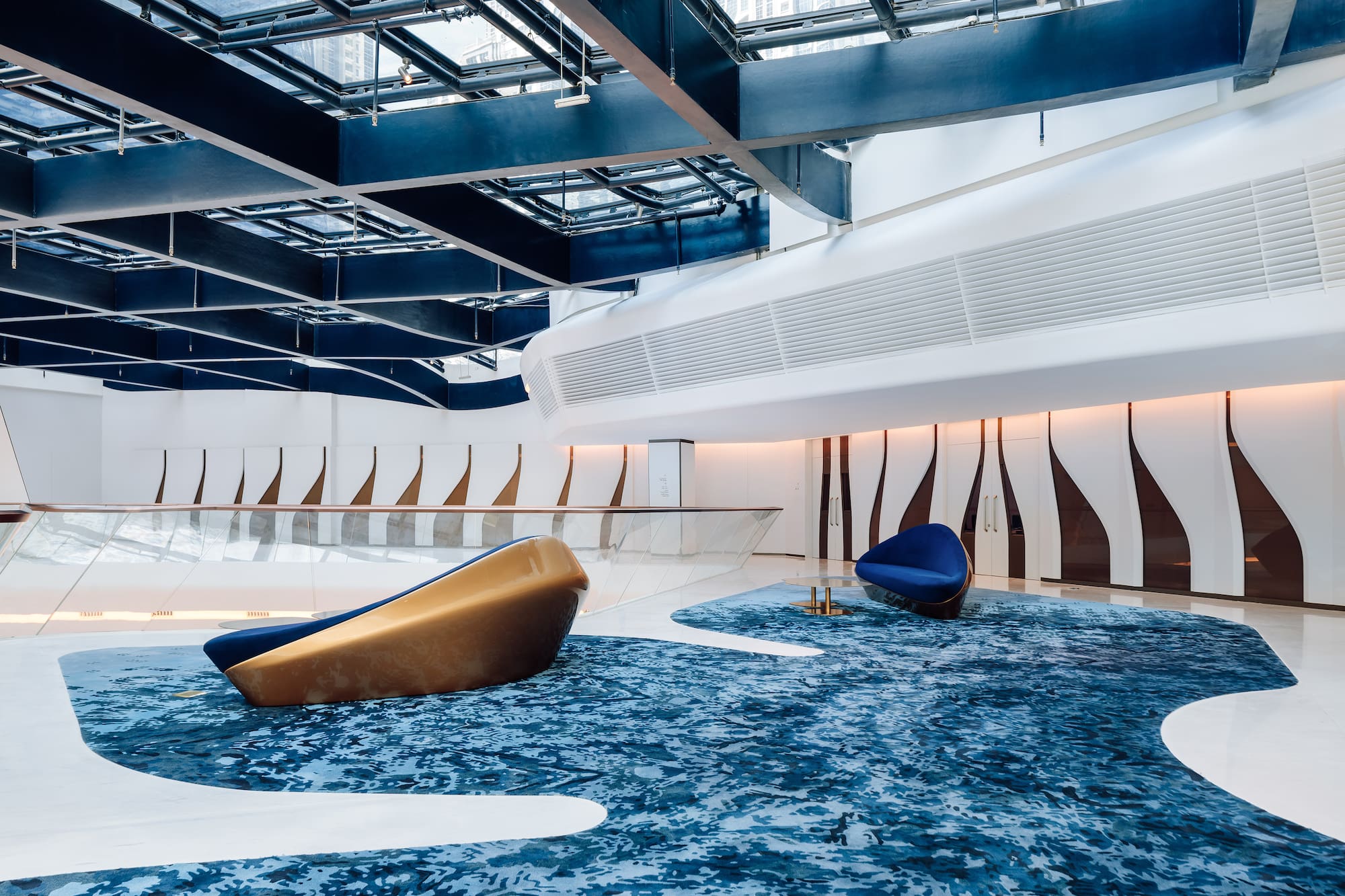 Contemporary lobby with blue ocean-inspired carpet and sculptural seating.