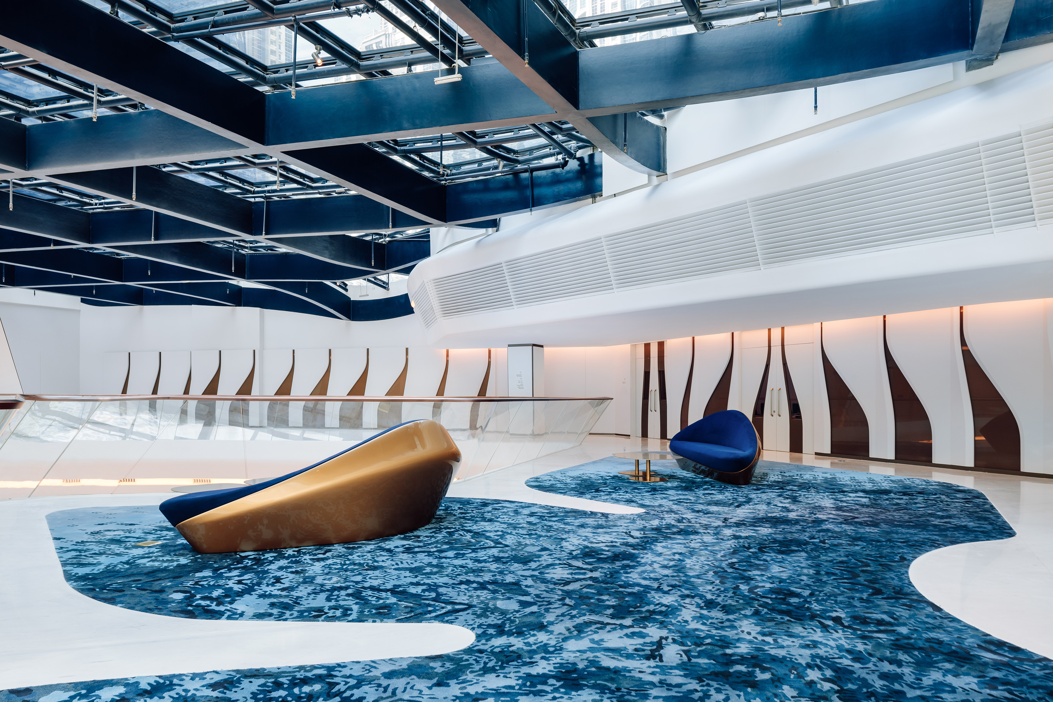 Contemporary lobby with blue ocean-inspired carpet and sculptural seating.