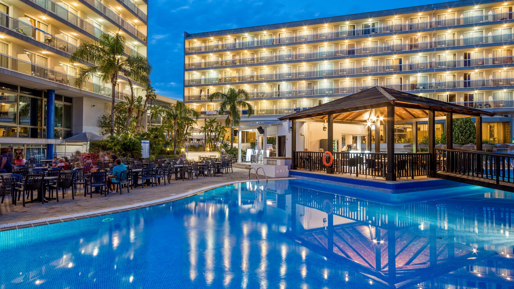 a pool with tables and chairs in front of a building