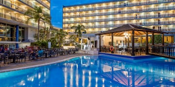 a pool with tables and chairs in front of a building
