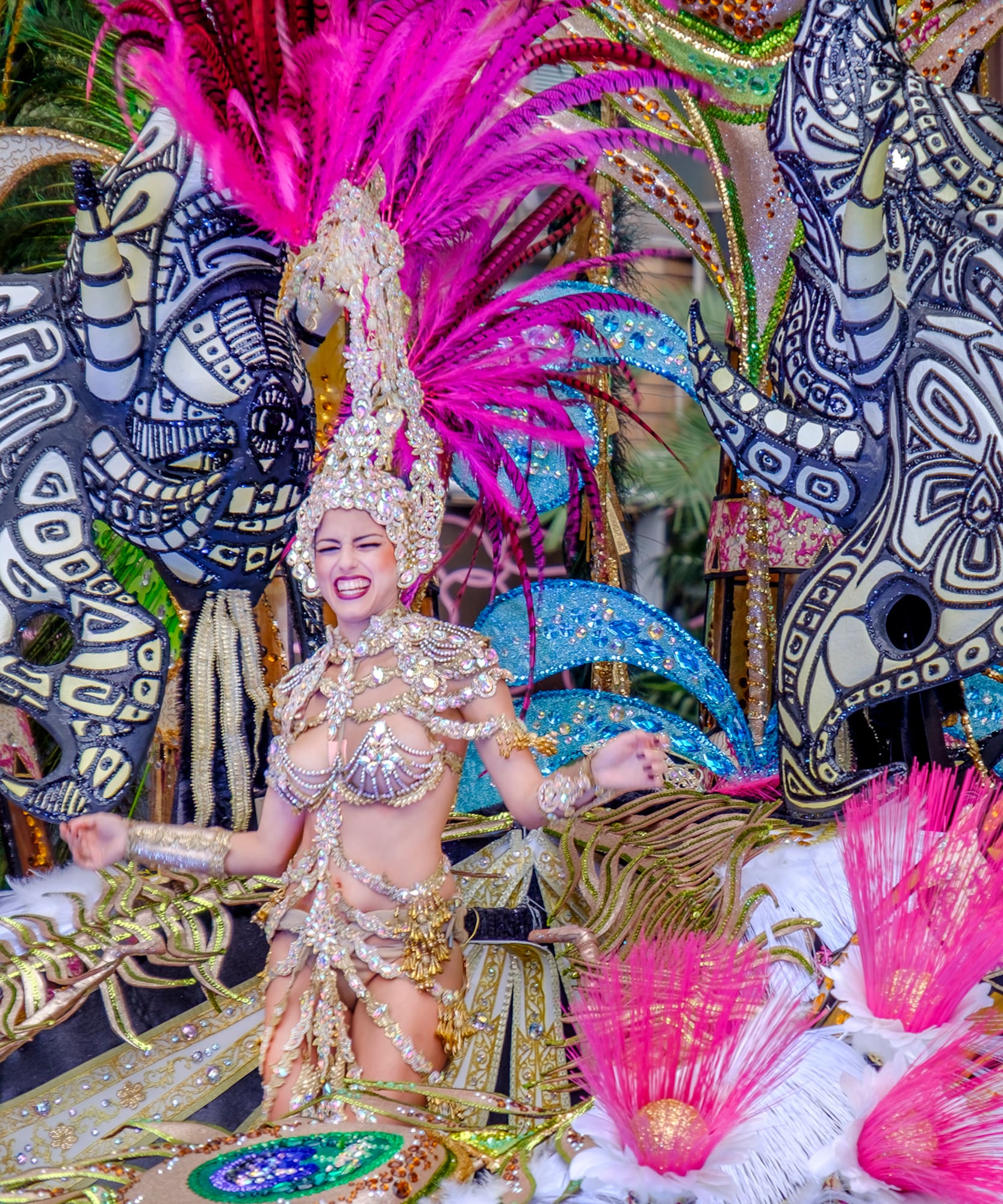 Reina de carnaval con vestido de oro y plumas fucsia, desfile festivo.