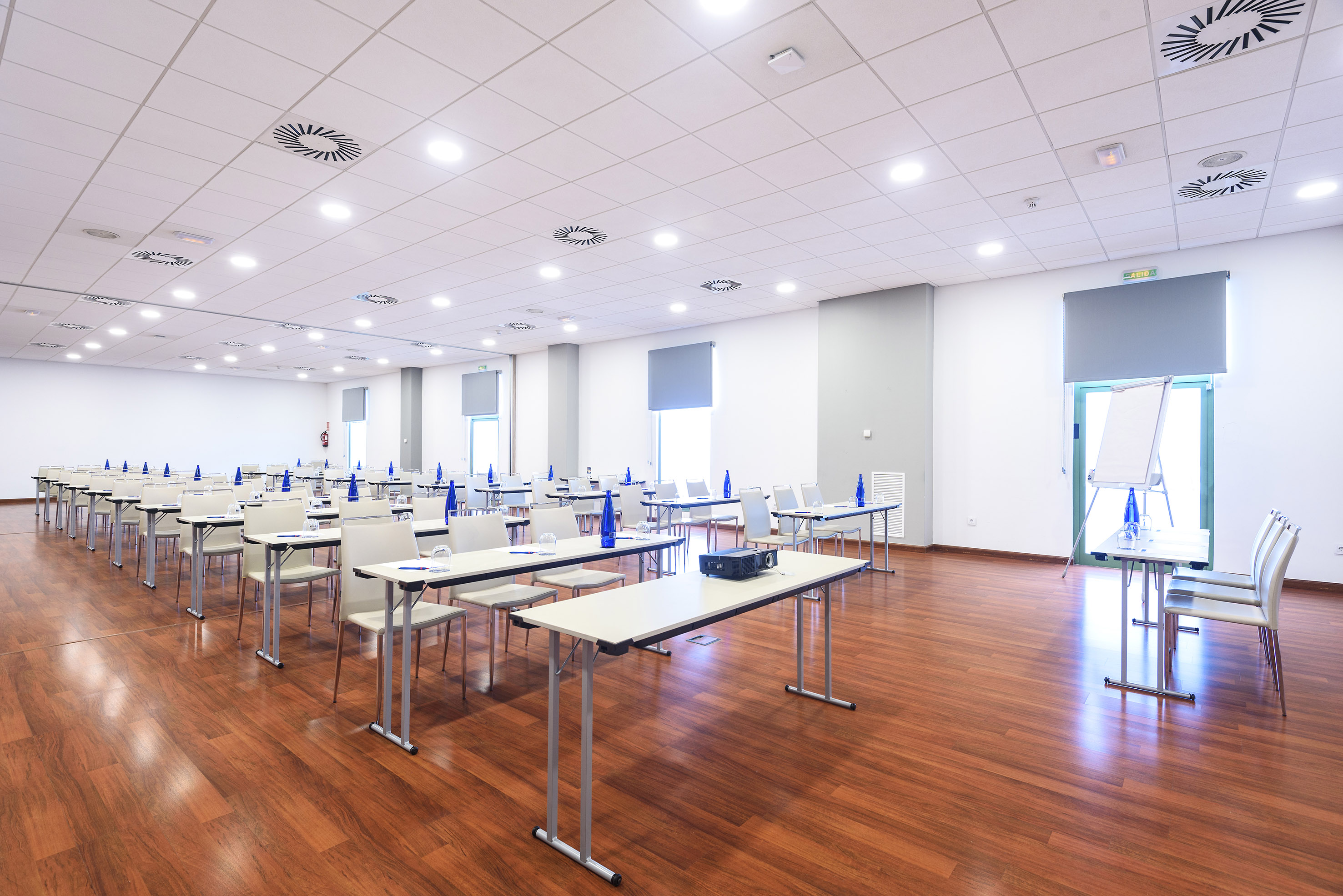 Empty modern conference room with classroom seating, projector, and wood floors.